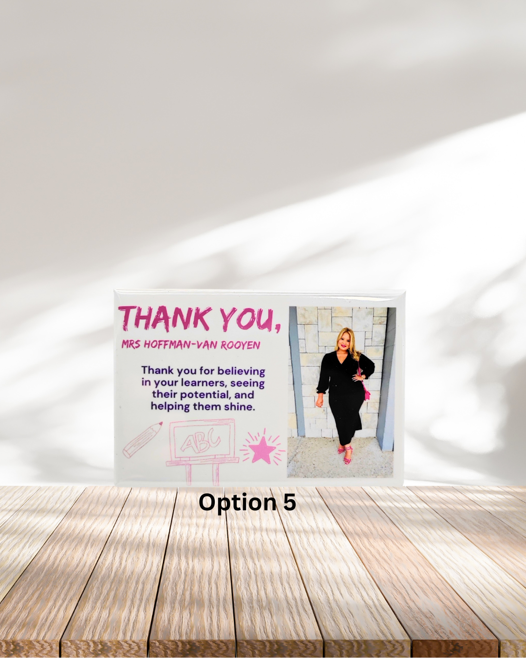 Poster with a woman in a black outfit on a wooden surface and white wall background